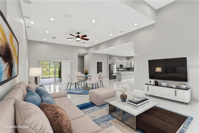 living room with marble finish floor, a high ceiling, visible vents, and recessed lighting