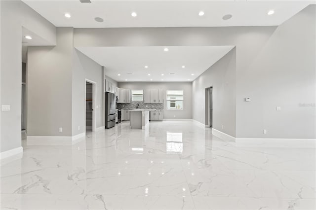 unfurnished living room featuring baseboards, marble finish floor, a sink, and recessed lighting