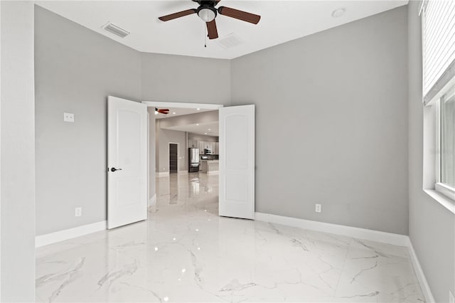 empty room with ceiling fan, visible vents, and baseboards