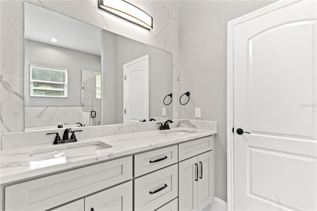 full bathroom with double vanity, a sink, and a marble finish shower