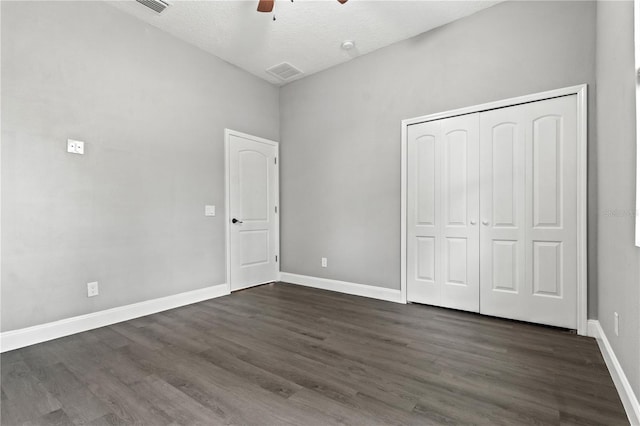 unfurnished bedroom featuring baseboards, a closet, visible vents, and dark wood-style flooring