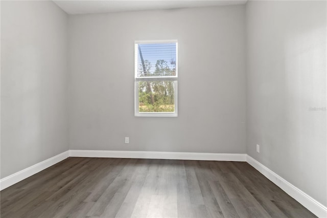 unfurnished room with baseboards and dark wood-type flooring