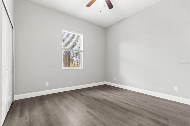 spare room with dark wood-style floors, baseboards, and a ceiling fan