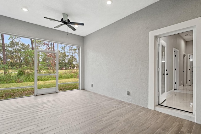 spare room with light wood-style floors, recessed lighting, a textured wall, and ceiling fan