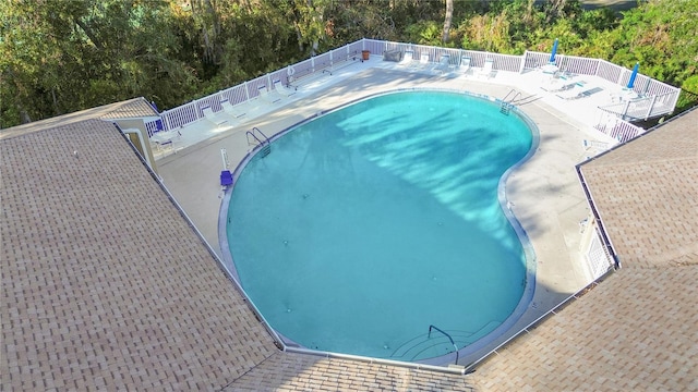 community pool with a patio area and fence