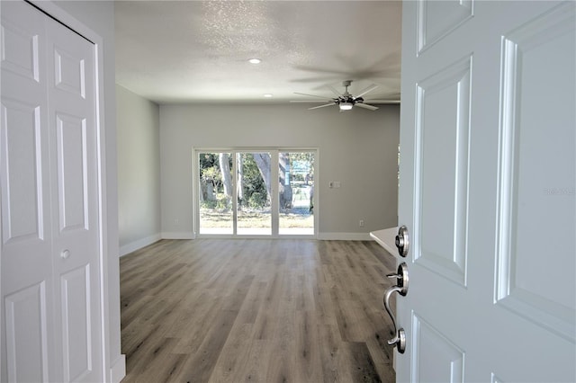 interior space with ceiling fan, light wood-type flooring, and a textured ceiling