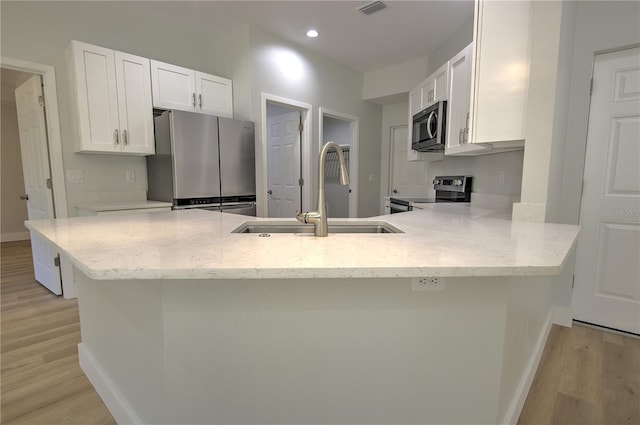 kitchen featuring sink, kitchen peninsula, white cabinets, and appliances with stainless steel finishes