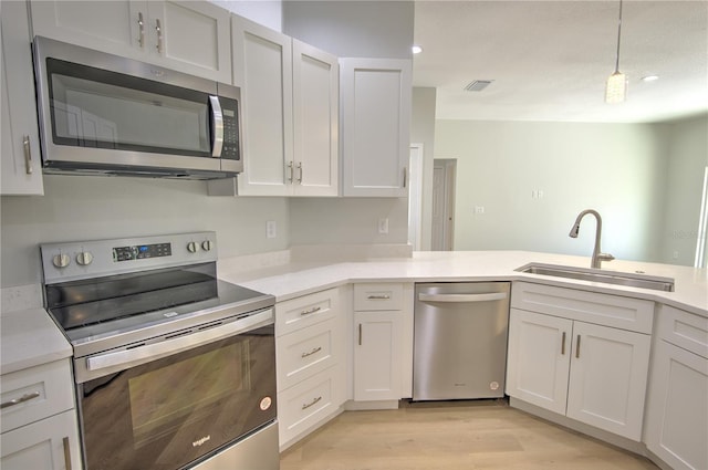 kitchen featuring pendant lighting, appliances with stainless steel finishes, sink, and white cabinets