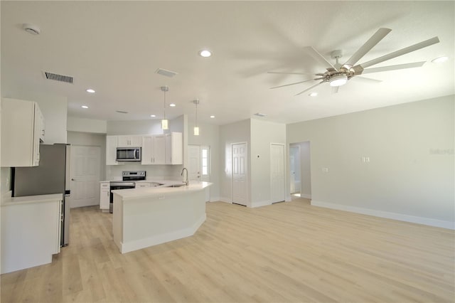 kitchen with decorative light fixtures, light wood-type flooring, kitchen peninsula, stainless steel appliances, and white cabinets