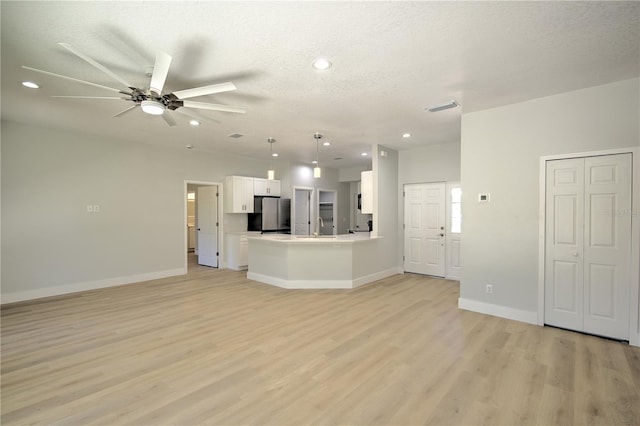 unfurnished living room featuring ceiling fan, a textured ceiling, and light hardwood / wood-style flooring