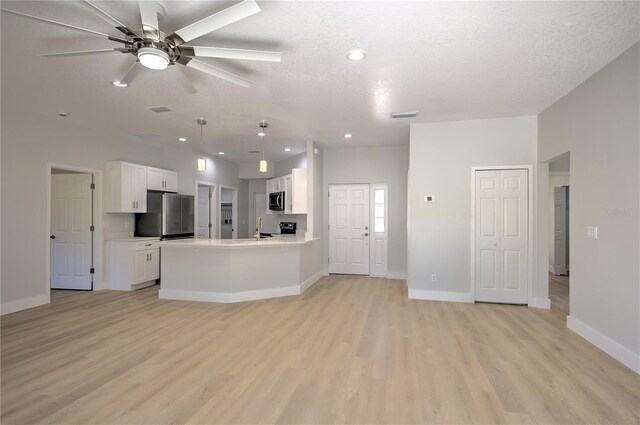 kitchen featuring white cabinetry, decorative light fixtures, stainless steel appliances, and a textured ceiling