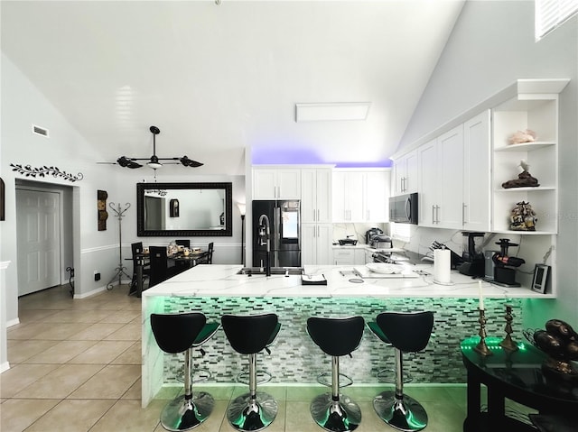 kitchen featuring black refrigerator, white cabinetry, and a breakfast bar area