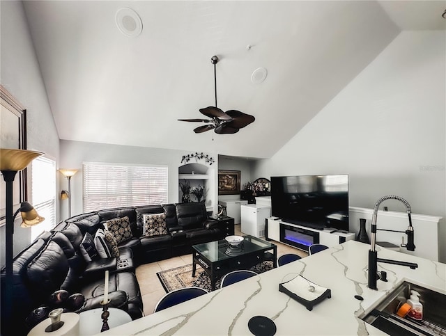 tiled living room with ceiling fan, sink, and high vaulted ceiling