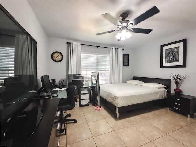 bedroom with ceiling fan, light tile patterned floors, and a textured ceiling