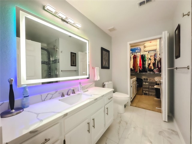 bathroom with vanity, toilet, and a shower with door