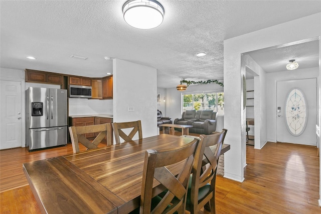 dining area with a textured ceiling and light wood-type flooring