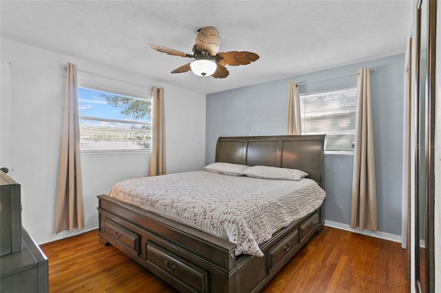 bedroom featuring dark hardwood / wood-style floors, ceiling fan, and a textured ceiling