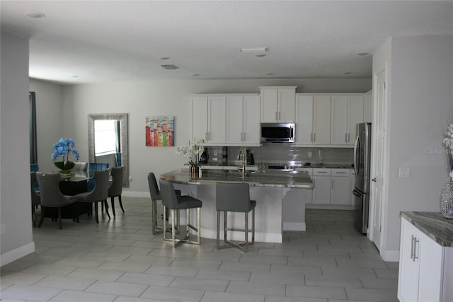 kitchen featuring a breakfast bar area, white cabinetry, sink, and appliances with stainless steel finishes