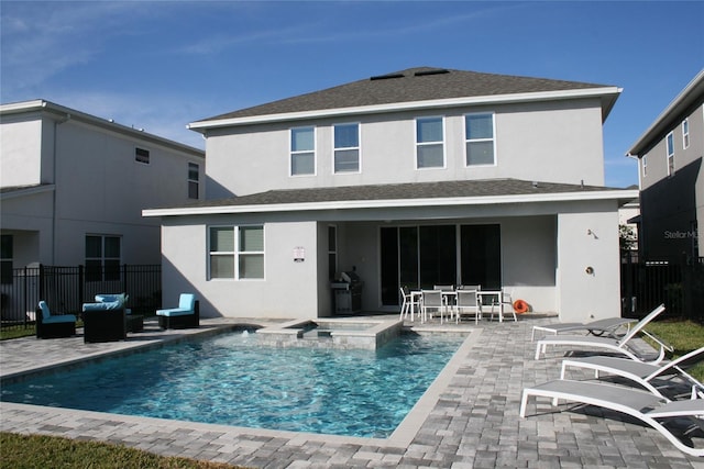 rear view of house featuring a patio area and a swimming pool with hot tub