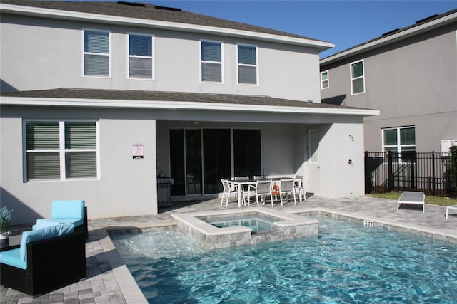 rear view of property with a patio and a pool with hot tub