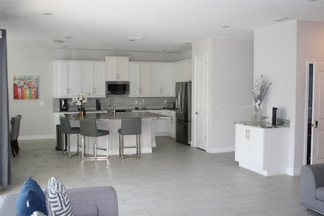 kitchen featuring appliances with stainless steel finishes, tasteful backsplash, a breakfast bar, sink, and white cabinets