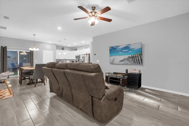 living room with light hardwood / wood-style flooring and ceiling fan with notable chandelier