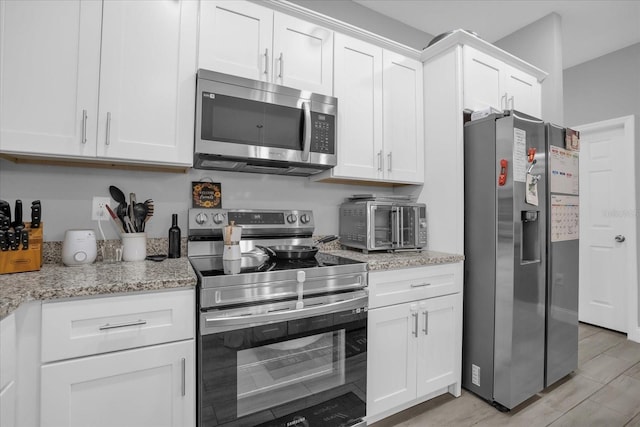 kitchen with white cabinetry, light stone counters, and appliances with stainless steel finishes