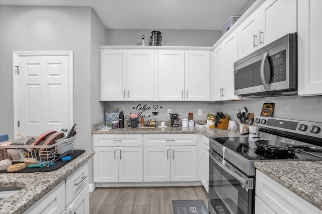 kitchen with white cabinets, stainless steel appliances, and light stone countertops