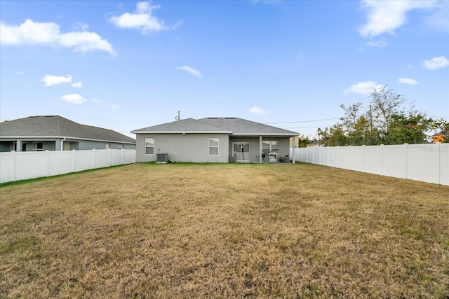 back of house with central air condition unit and a lawn