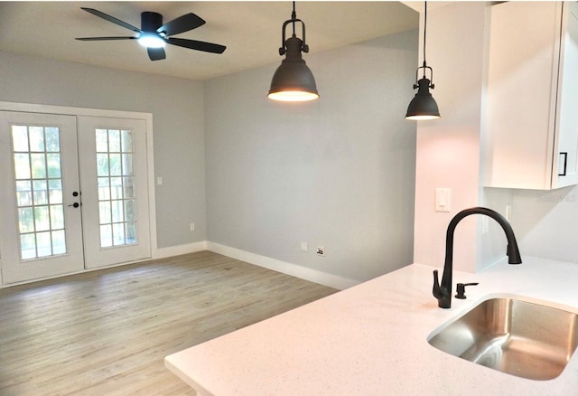 kitchen featuring french doors, sink, ceiling fan, decorative light fixtures, and wood-type flooring