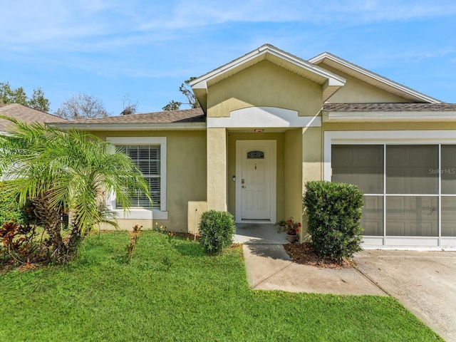 entrance to property featuring a garage and a lawn