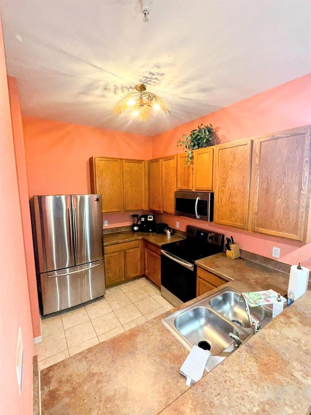 kitchen with appliances with stainless steel finishes, sink, and light tile patterned flooring