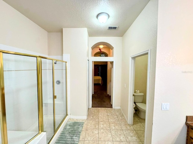 bathroom with built in features, tile patterned floors, an enclosed shower, a textured ceiling, and toilet