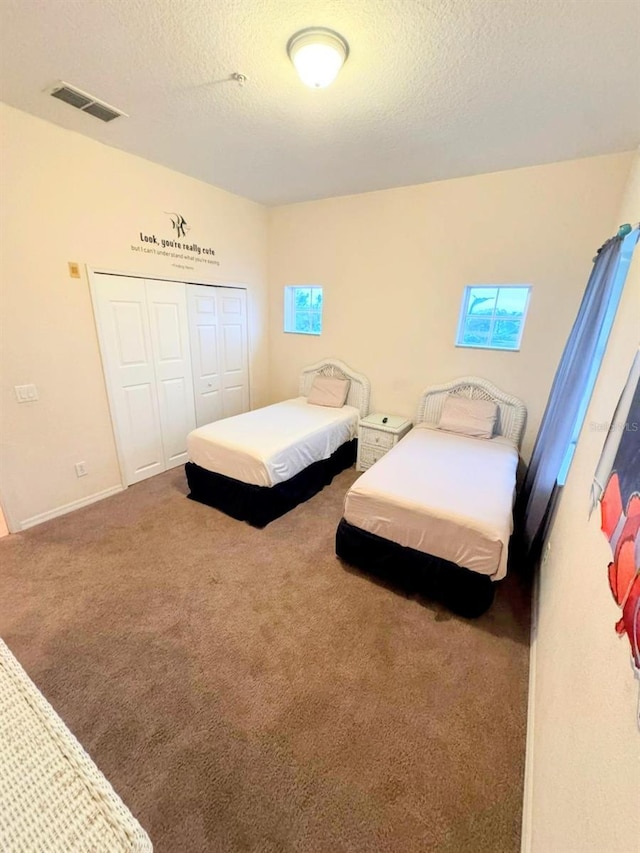 carpeted bedroom with a textured ceiling and a closet