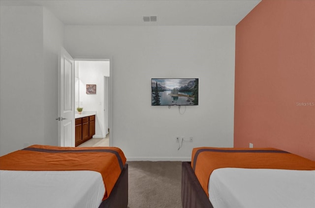 bedroom featuring ensuite bath and light colored carpet