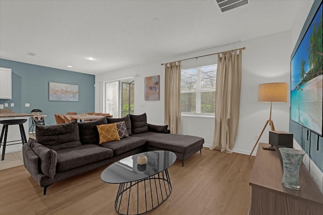 living area featuring baseboards, visible vents, and light wood-type flooring