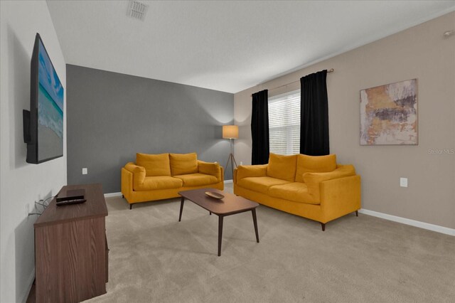 living area with visible vents, light carpet, and baseboards