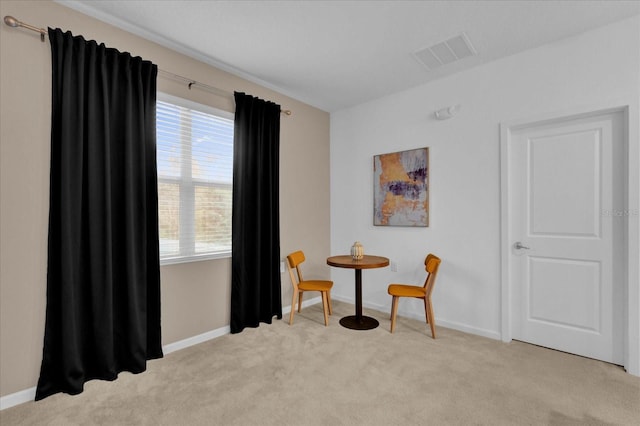 living area featuring baseboards, visible vents, and light carpet