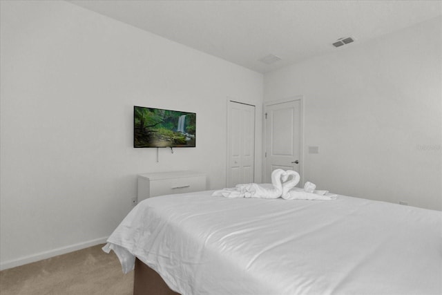 bedroom with baseboards, visible vents, a closet, and light carpet