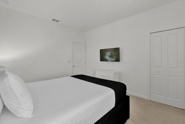 bedroom featuring light carpet, visible vents, baseboards, and a closet