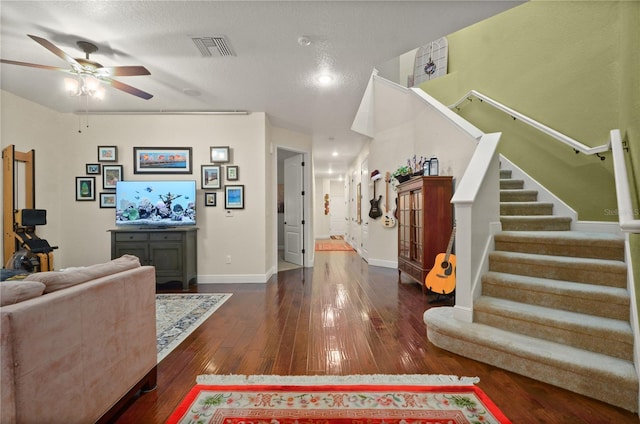 living room featuring ceiling fan, a textured ceiling, and dark wood-type flooring