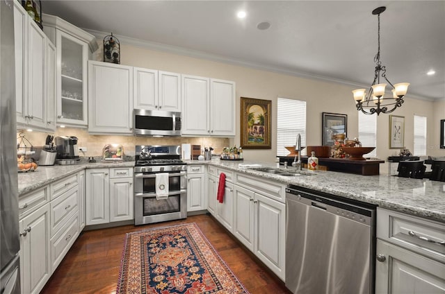 kitchen featuring dark wood-type flooring, crown molding, appliances with stainless steel finishes, a notable chandelier, and white cabinetry