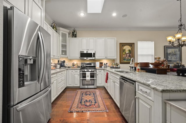 kitchen with hanging light fixtures, dark hardwood / wood-style floors, appliances with stainless steel finishes, white cabinets, and ornamental molding