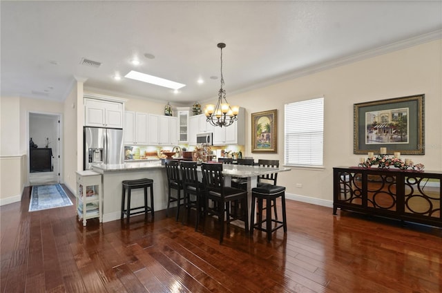 dining area with dark hardwood / wood-style floors, crown molding, and a notable chandelier