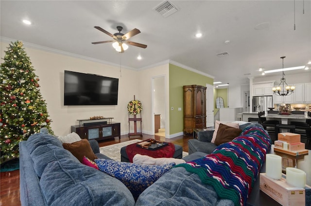 living room with ceiling fan with notable chandelier, wood-type flooring, and ornamental molding