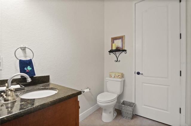 bathroom with toilet, vanity, and tile patterned floors