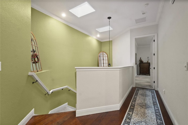 corridor with a skylight, crown molding, and hardwood / wood-style flooring