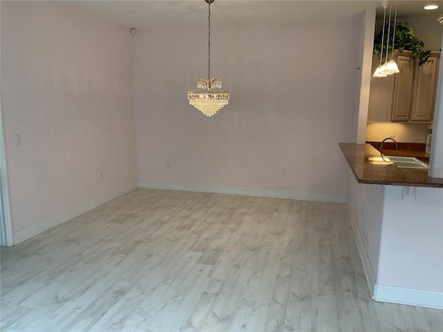 unfurnished dining area with an inviting chandelier, sink, and light hardwood / wood-style floors