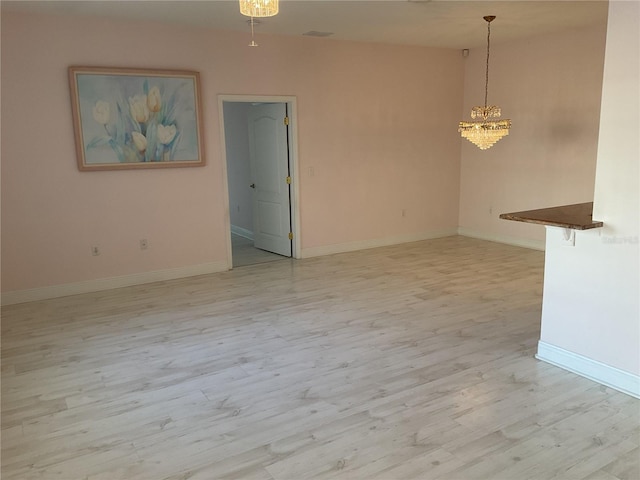 spare room with a chandelier and light hardwood / wood-style floors