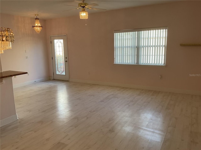 interior space with ceiling fan with notable chandelier and light hardwood / wood-style flooring